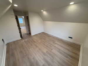 Bonus room with lofted ceiling and light hardwood / wood-style floors