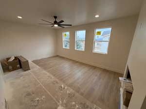 Unfurnished living room with ceiling fan, a textured ceiling, and hardwood / wood-style floors