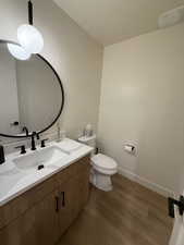 Bathroom with hardwood / wood-style floors, vanity, and toilet