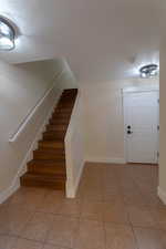 Interior space with a textured ceiling and light tile patterned floors