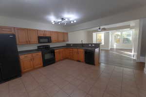 Kitchen with black appliances, sink, kitchen peninsula, ceiling fan, and light hardwood / wood-style flooring