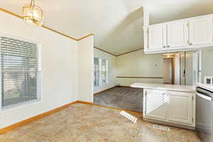 Kitchen featuring crown molding, white cabinetry, kitchen peninsula, and decorative light fixtures