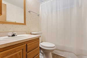 Full bathroom featuring toilet, vanity, and shower / bathtub combination with curtain