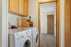 Washroom featuring cabinets, carpet floors, and washing machine and dryer