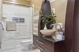 Full bathroom with vanity, toilet, tile patterned flooring, and bath / shower combo with glass door