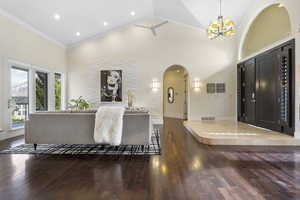 Living room featuring crown molding, a notable chandelier, dark hardwood / wood-style floors, and high vaulted ceiling