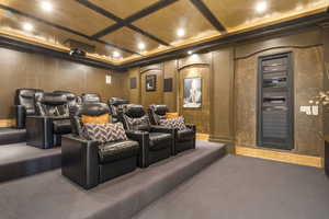 Carpeted cinema room with coffered ceiling and crown molding