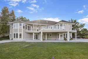 Rear view of house featuring a balcony, french doors, a yard, and a patio