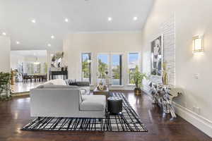 Living room featuring dark wood-type flooring, crown molding, french doors, and a wealth of natural light