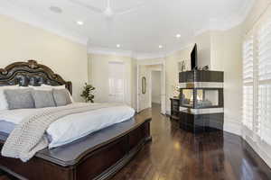 Bedroom featuring dark wood-type flooring, ceiling fan, and crown molding