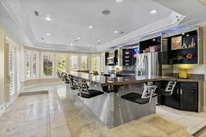 Kitchen featuring sink, a kitchen breakfast bar, dark stone countertops, and a raised ceiling