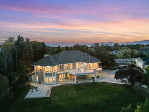 Back house at dusk with a patio area, a mountain view, and a yard