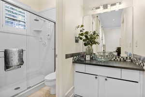 Bathroom with vanity, toilet, ornamental molding, and a shower with shower door