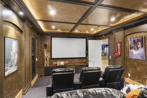 Carpeted home theater room featuring coffered ceiling