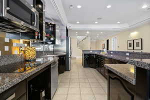 Kitchen with dark stone counters, light tile patterned flooring, sink, dark brown cabinetry, and stainless steel appliances