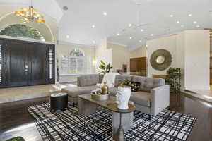 Living room featuring a chandelier, crown molding, wood-type flooring, and high vaulted ceiling