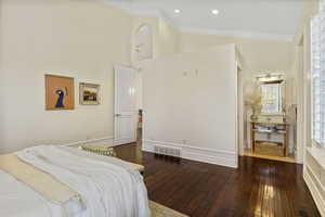 Bedroom featuring a towering ceiling, ornamental molding, and dark hardwood / wood-style flooring