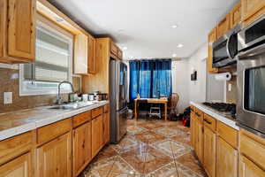 Kitchen featuring decorative backsplash, tile countertops, sink, light tile patterned floors, and appliances with stainless steel finishes