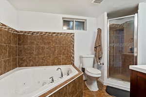 Full bathroom with toilet, tile patterned flooring, separate shower and tub, vanity, and a textured ceiling