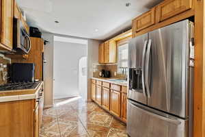 Kitchen with appliances with stainless steel finishes, tile countertops, tasteful backsplash, and sink