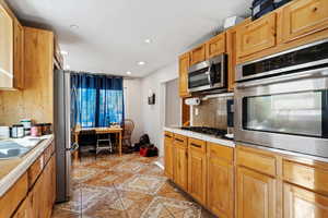 Kitchen featuring sink, light tile patterned flooring, stainless steel appliances, and backsplash