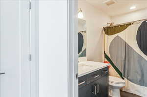 Full bathroom with vanity, hardwood / wood-style floors, toilet, and shower / bath combination with curtain