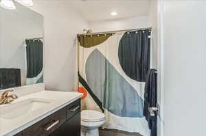 Bathroom featuring toilet, hardwood / wood-style floors, a shower with curtain, and vanity