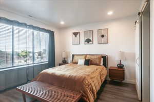 Bedroom featuring dark wood-type flooring and a barn door