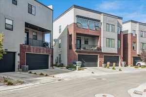 View of front of home with central AC, a garage, and a balcony