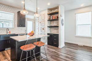 Kitchen with sink, a center island, a kitchen breakfast bar, pendant lighting, and dark hardwood / wood-style floors