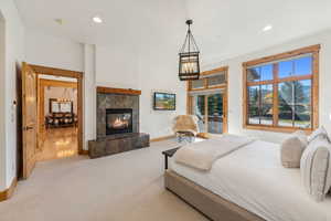 Bedroom featuring a tiled fireplace and light colored carpet