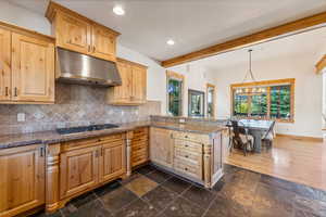 Kitchen with stainless steel gas cooktop, kitchen peninsula, a notable chandelier, and a wealth of natural light