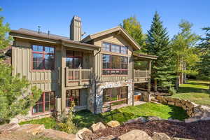 Rear view of property featuring a lawn and a balcony