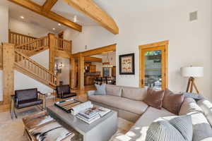 Living room featuring beam ceiling, high vaulted ceiling, and a chandelier