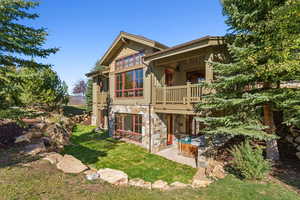 Back of property with a patio area, a lawn, and a balcony