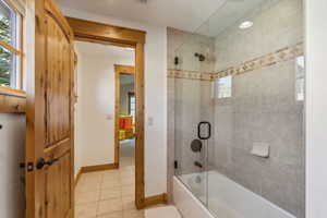 Bathroom featuring tile patterned flooring and bath / shower combo with glass door