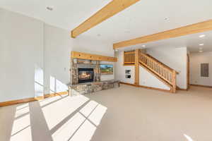 Unfurnished living room featuring electric panel, a stone fireplace, and carpet floors