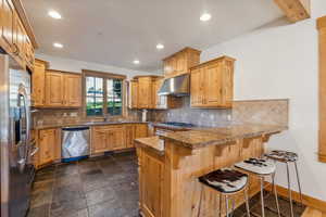 Kitchen featuring appliances with stainless steel finishes, sink, a kitchen bar, kitchen peninsula, and extractor fan