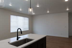 Kitchen featuring decorative light fixtures, light stone counters, dark hardwood / wood-style floors, and sink