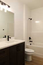 Full bathroom featuring hardwood / wood-style flooring, vanity, toilet, and bathtub / shower combination