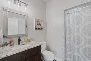 Bathroom featuring toilet, curtained shower, and vanity