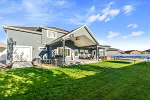 Rear view of property featuring a patio area, a lawn, a trampoline, and ceiling fan