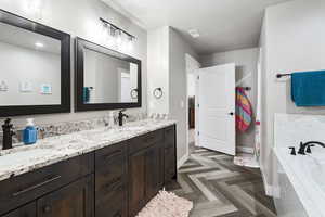 Bathroom featuring vanity, tiled bath, and tile floors