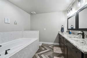 Bathroom featuring vanity, parquet floors, a textured ceiling, and a washtub