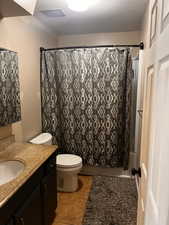 Full bathroom with toilet, shower / bathtub combination with curtain, vanity, and tile patterned flooring