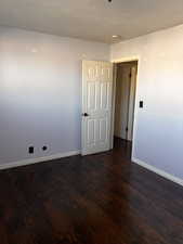 Empty room featuring a textured ceiling and dark wood-type flooring