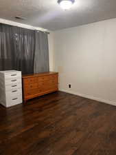 Unfurnished bedroom featuring a textured ceiling and dark hardwood / wood-style flooring