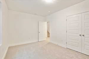 Unfurnished bedroom with a closet and light colored carpet