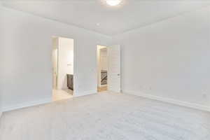 Unfurnished bedroom with ensuite bathroom and light colored carpet