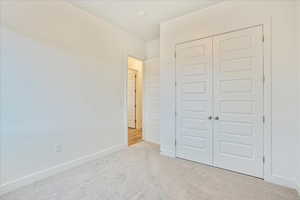 Unfurnished bedroom featuring a closet and light colored carpet